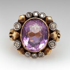 This captivating vintage 19K yellow gold ring is centered with one (1), bezel set, oval mixed cut natural amethyst and is bordered with ten (10) old European/single cut diamonds set into sterling silver bezel setting. The shank has a fluted design and is stamped 19K. The ring measures 17.2mm at the top, rises 6.9mm above the finger, tapering to 3.1mm wide and 0.9mm thick at the base of the shank. This ring is currently a size 7.25. Heirloom Amethyst Ring In Yellow Gold With Bezel Setting, Luxury Gold Amethyst Ring With Rose Cut Diamonds, Oval Amethyst Ring With Bezel Setting For Formal Occasions, Oval Amethyst Ring With Bezel Setting, Luxury Yellow Gold Amethyst Ring With Rose Cut Diamonds, Heirloom Purple Ring With Rose Cut Diamonds, Oval Amethyst Multi-stone Ring In Yellow Gold, Formal Gold Amethyst Ring With Rose Cut Diamonds, Formal Rose Cut Amethyst Ring In Yellow Gold