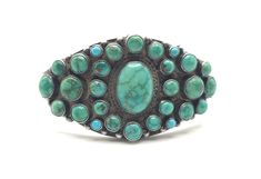 Vintage Cluster Turquoise and Sterling Silver Bracelet INCREDIBLE  Likely circa 1930's-40's, this piece is unmatched in its style, craftsmanship, condition, and age.  The stones have aged to a perfect green-blue, and the patina is just what you want for the age.  10/10! 28 cabochons of exquisite turquoise surround the center stone in it's braided silver frame The edge of the bracelet is accented with small silver rounds The braids of silver extend around the cuff, as well as the underside of the Vintage Turquoise Jewelry With Stones, Vintage Turquoise Stone Jewelry, Vintage Turquoise Round Cuff Bracelet, Vintage Green Multi-stone Turquoise Ring, Vintage Oval Multi-stone Bracelets, Green Multi-stone Vintage Turquoise Ring, Vintage Green Bracelet With Natural Stones, Vintage Green Bracelets With Natural Stones, Oval Turquoise Collectible Bracelet