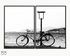 black and white photograph of a bicycle parked next to a lamp post on the beach