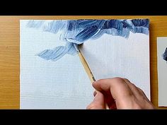 someone is painting something with blue and white colors on the paper, using a paint brush