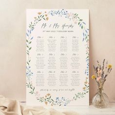 a wedding seating chart with flowers and greenery in vases next to it on a table