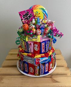 a cake made out of candy bars and candies on a wooden table next to a wall