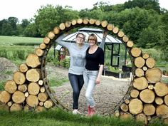 two women standing next to each other in front of a mirror made out of logs