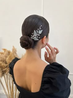 a woman in a black dress is holding her hand up to her face while wearing a hair comb