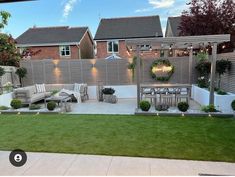 an outdoor patio with seating and lights on the walls, surrounded by green lawning