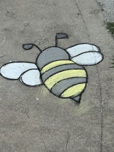 a drawing of a bee on the ground with yellow and gray stripes, painted in chalk