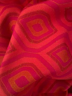 an orange and pink fabric with geometric design on the top, as if it were made from silk or polyester