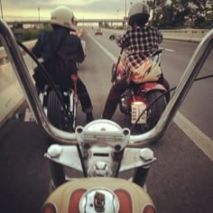 two people riding motorcycles on the road