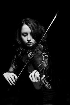 a woman is playing the violin in black and white