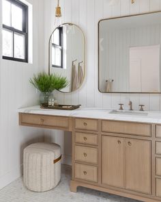 a bathroom with two sinks, mirrors and a stool in front of the mirror on the wall