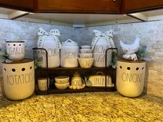 the kitchen counter is covered with white ceramic jars