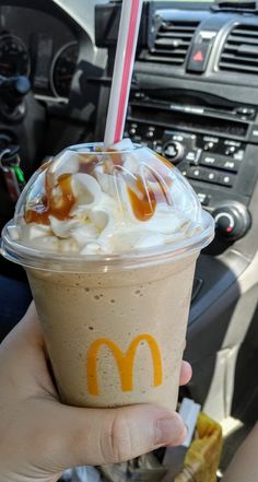 a person holding up a drink with whipped cream and caramel toppings on it