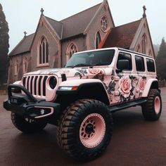 a pink jeep parked in front of a church with roses painted on it's side