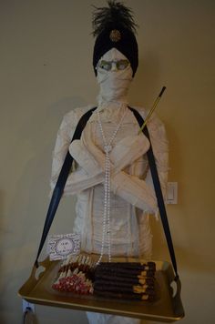 a cake made to look like a woman with glasses and pearls on her head is sitting on a tray in front of a wall