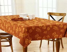 the table is covered with an orange and gold floral design, along with two brown chairs