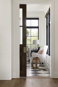 an open door leading to a living room with checkered flooring and white walls