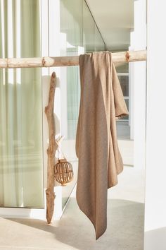 a towel hanging on the side of a glass wall next to a basket with a bird in it