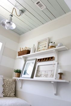 a white shelf with pictures and other items on it in the corner of a room