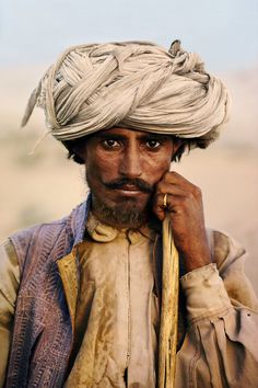 a man with a white turban on his head and wearing a ring around his neck