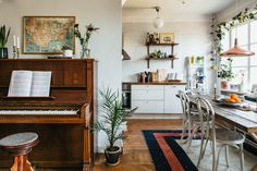 a living room filled with furniture and a wooden piano in front of a large window