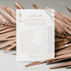 a wedding game with palm leaves and wine glasses on it, which says what is the groom's say?