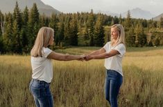 two women are holding hands in a field