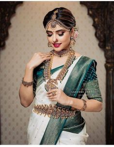 a woman in a green and white sari with gold jewelry on her neck,