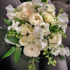 a bouquet of white flowers sitting on top of a gray couch next to a pillow