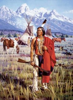 a native american man standing in the grass with two horses behind him and mountains in the background