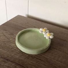 three white flowers in a green bowl on a wooden table