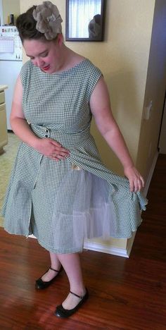 a woman in a dress standing on a hard wood floor with her hands on her hips