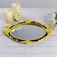 an ornate gold and black tray with flowers on the table next to candles, vases and candle holders