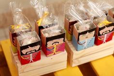 three small boxes with candy wrapped in cellophane and tied with yellow ribbon, sitting on a wooden table