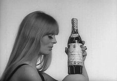 a woman holding a bottle of berry wine in front of her face and looking at it