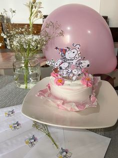 a birthday cake on a table with balloons and flowers