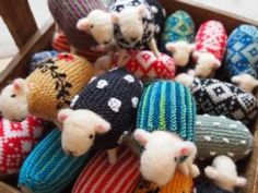 several knitted animals are in a wooden box with white and black designs on them