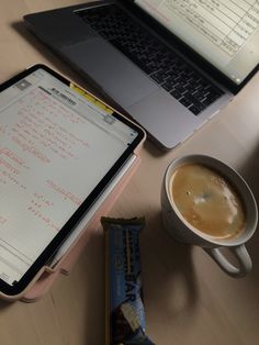 an open laptop computer sitting on top of a wooden table next to a cup of coffee