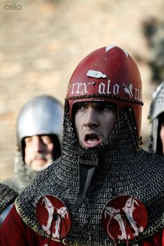 a group of men dressed in armor and helmets standing next to each other with their mouths open