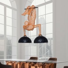 a dining room table with two chairs and a sculpture hanging from it's ceiling