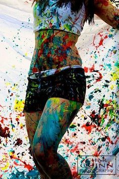 a woman is covered in paint and posing for the camera with her hands on her hips