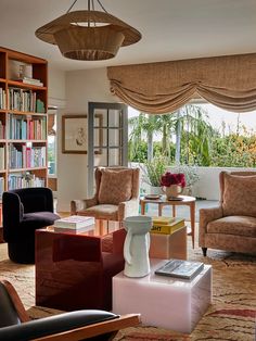 a living room filled with lots of furniture and bookshelves next to a window