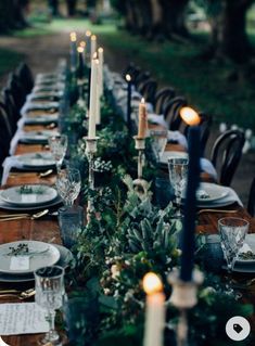 a long table is set with candles, plates and place settings for an elegant dinner