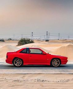 a red sports car parked in the sand dunes