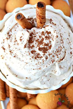 a white bowl filled with whipped cream and cinnamon sticks sticking out of it's top