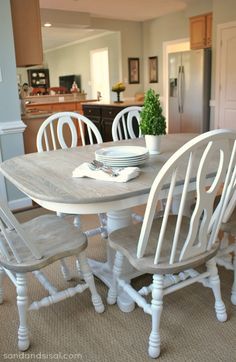 a dining room table with white chairs and a potted plant on top of it