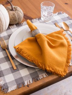 a white plate topped with a yellow napkin next to a fork and knife on top of a wooden table