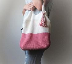 a woman holding a crocheted bag with the word pattern written on it in white and pink