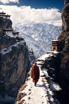 a monk walking on the edge of a cliff with snow covered mountains in the background