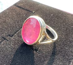 Celebrate the beauty of the cosmos with the stunning Pink Sapphire Silver Ring. The ring features a raw natural pink sapphire gemstone with brilliant fuchsia to dark pink color. Only one bespoke ring in UK Size L/size 51 (11mm dia) is available.   All photos attached are in natural sunlight. Colour looks darker as per amount of sunlight and skin tone.  As per Vedic Astrology, Ratnaraj' or King of Gems stone harnesses positive, life giving energy of the Sun. Ruby improves relationship with father making this ring a perfect gift for a daughter or anyone who loves the beauty of the universe. Whether for special occasions or everyday wear, the PadmaMalini Ring is a beautiful piece that will evoke positive vibrations and bring a touch of cosmic beauty to any outfit. Which finger to wear pink sa Luxury Pink Sapphire Birthstone Ring, Heirloom Pink Sapphire Gemstone Ring, Pink Sapphire Ring In Sterling Silver, Pink Sapphire Gemstones As A Gift, Pink Sapphire Birthstone Ring, Round Shape For Gift, Dark Pink Color, Sapphire Silver Ring, Handmade Silver Ring, Bespoke Rings