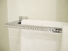 a towel rack in the corner of a bathroom with white towels and crystal beads on it